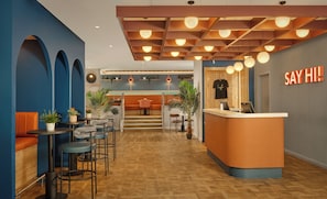 Un intérieur moderne comprenant un comptoir d’accueil, un espace salon et un escalier menant à un deuxième étage.