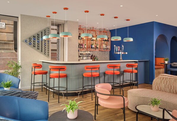 A bar area with multiple stools, a bar counter, and a variety of bottles.