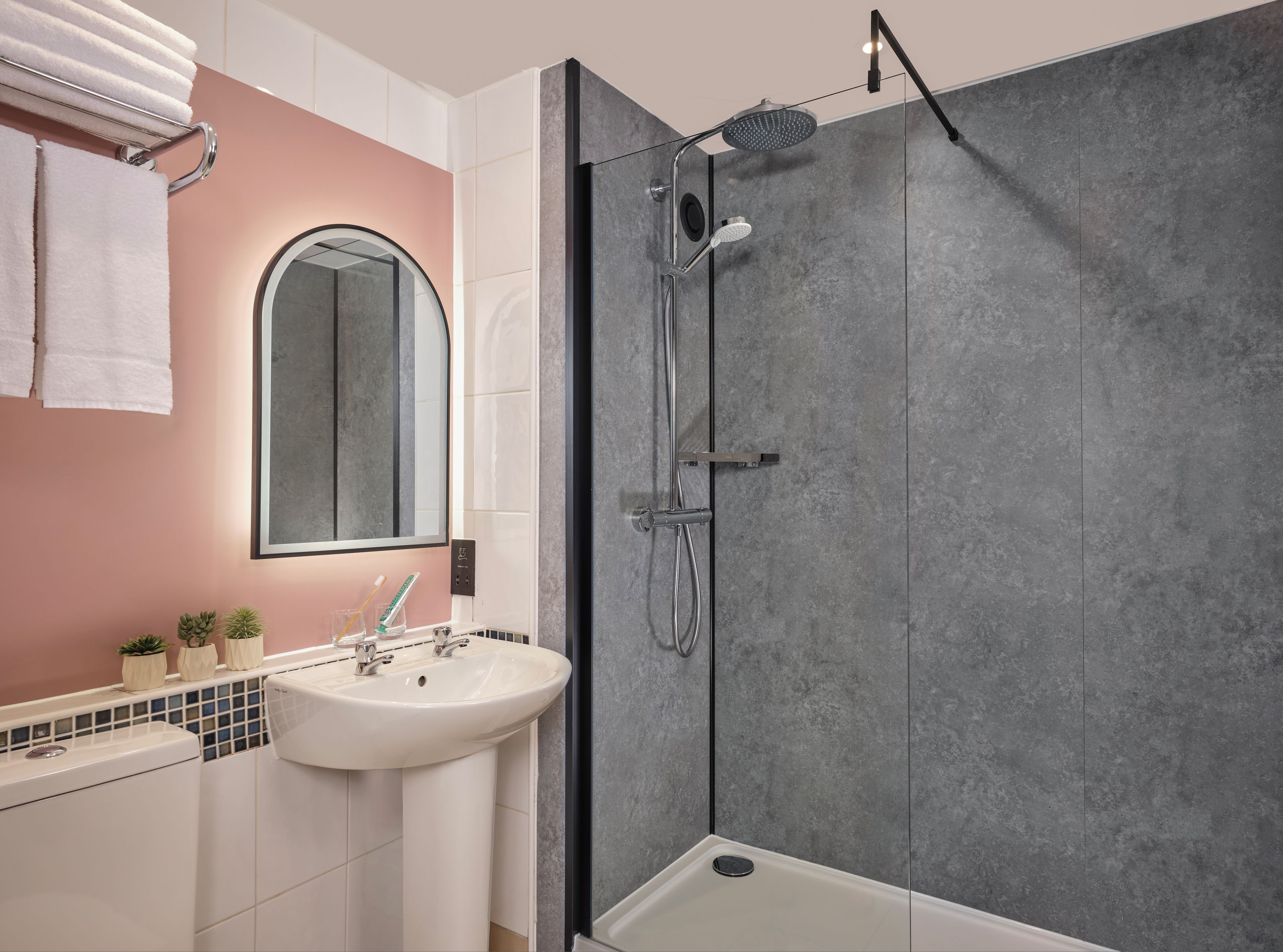 A modern bathroom with a glass-enclosed shower, a white sink, and a mirror above it.