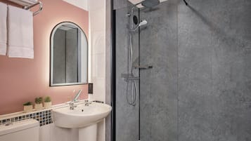 A modern bathroom with a glass-enclosed shower, a white sink, and a mirror above it.