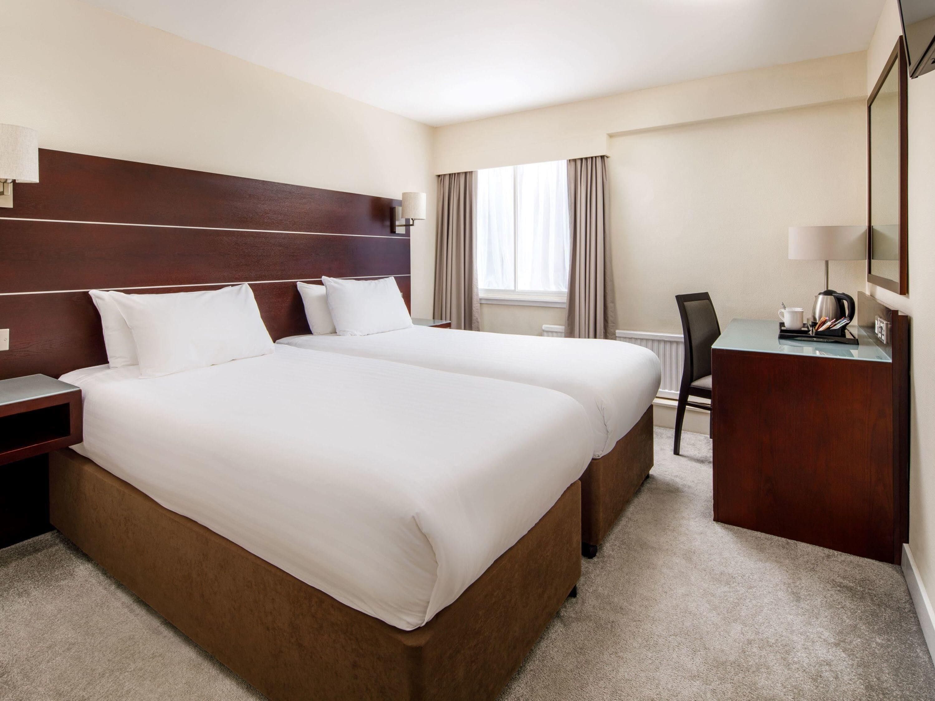 A hotel room with a large bed, a desk, and a chair.
