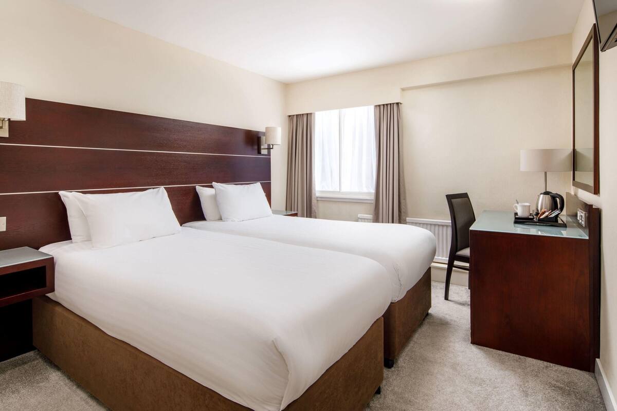 Une chambre d’hôtel avec un grand lit, un bureau et une chaise.