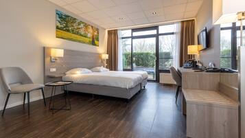 A modern hotel room with a bed, a desk, a chair, a small table, and a painting on the wall.
