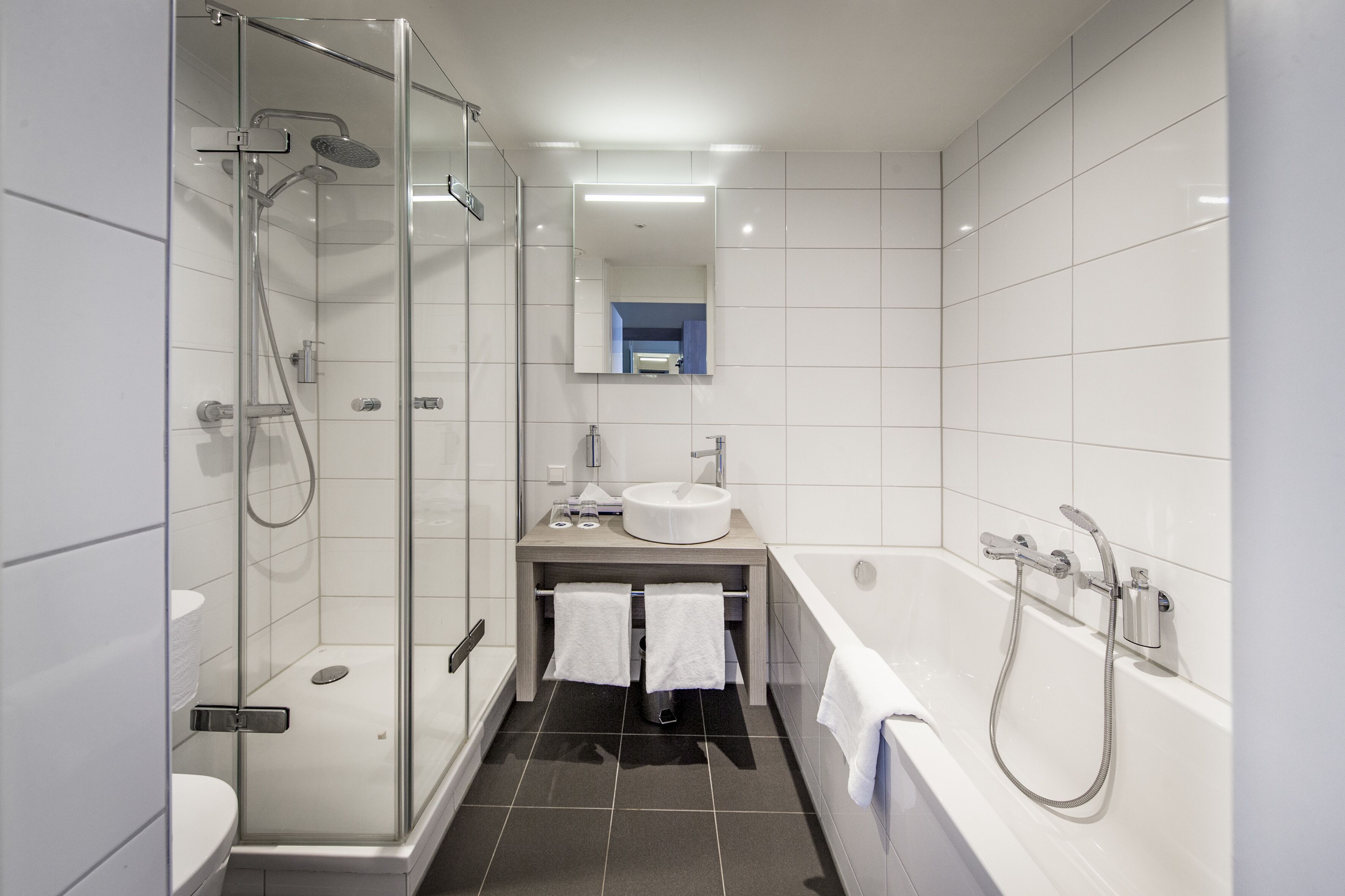 A modern bathroom with a glass-enclosed shower, a white sink, and a bathtub.