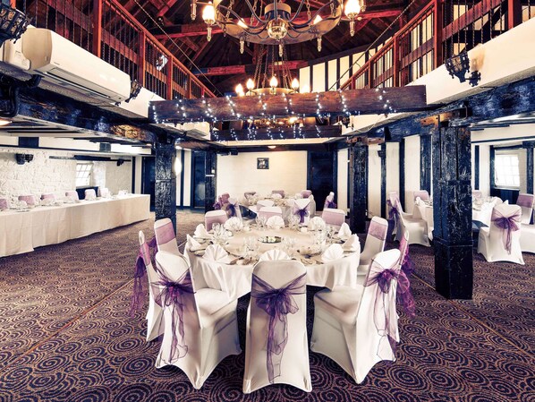 A banquet hall with round tables set for a formal event, featuring white tablecloths and chairs with purple sashes. - Mercure Perth Hotel (Perth)