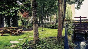 A garden with picnic tables, a small waterfall, and a wooden bridge.
