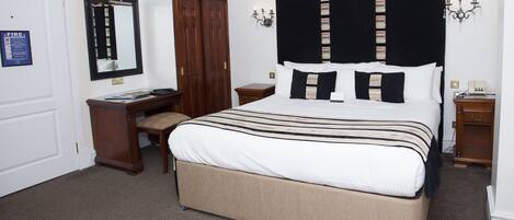 Un dormitorio con una cama grande, un escritorio, una silla, un armario y un espejo.