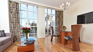 A modern living room with a sofa, a glass coffee table, a dining table with chairs, and a TV mounted on the wall. - Aberdeen Douglas Hotel (Aberdeen)
