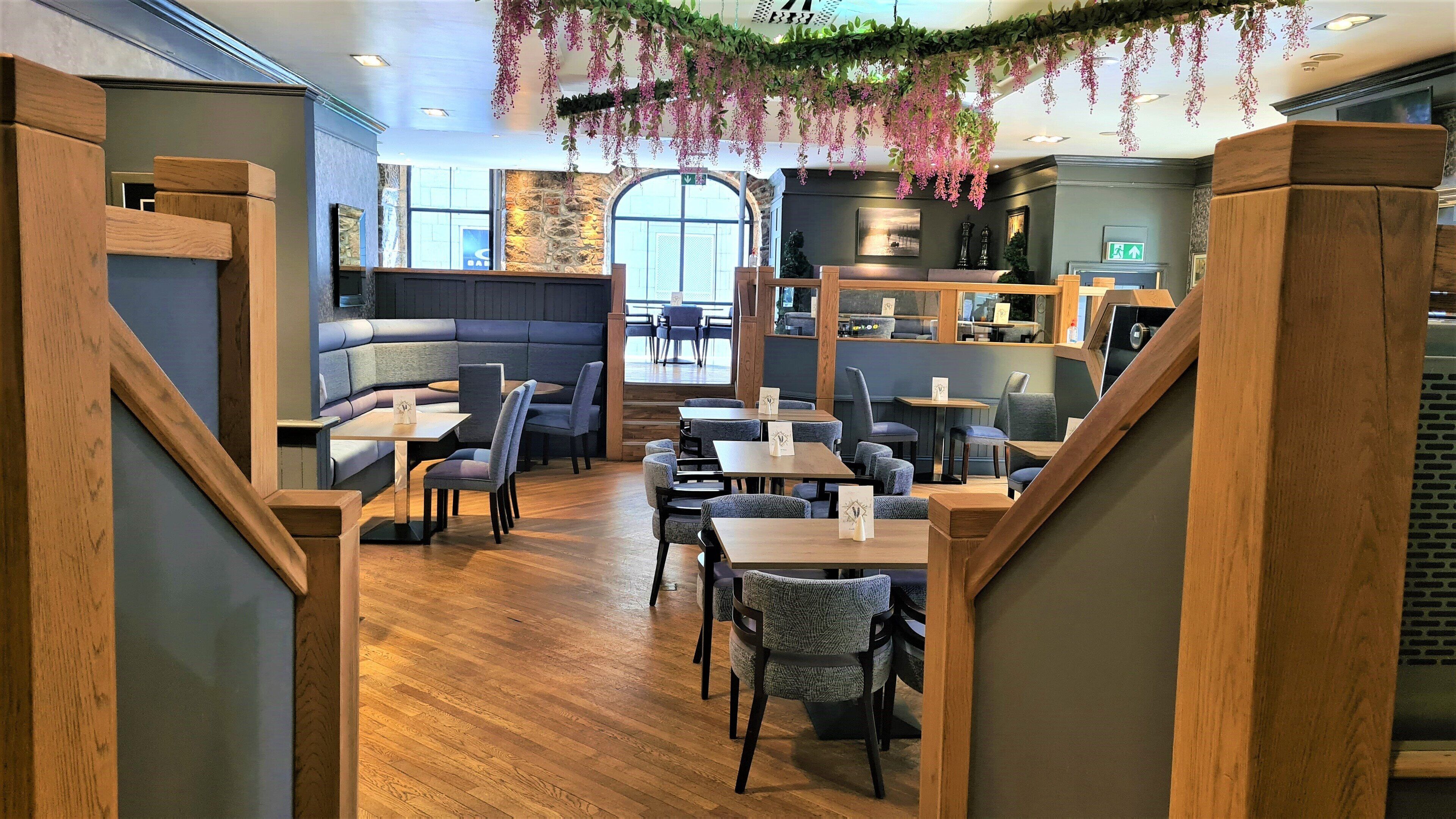 A restaurant with wooden furniture, a stone wall, and hanging plants.