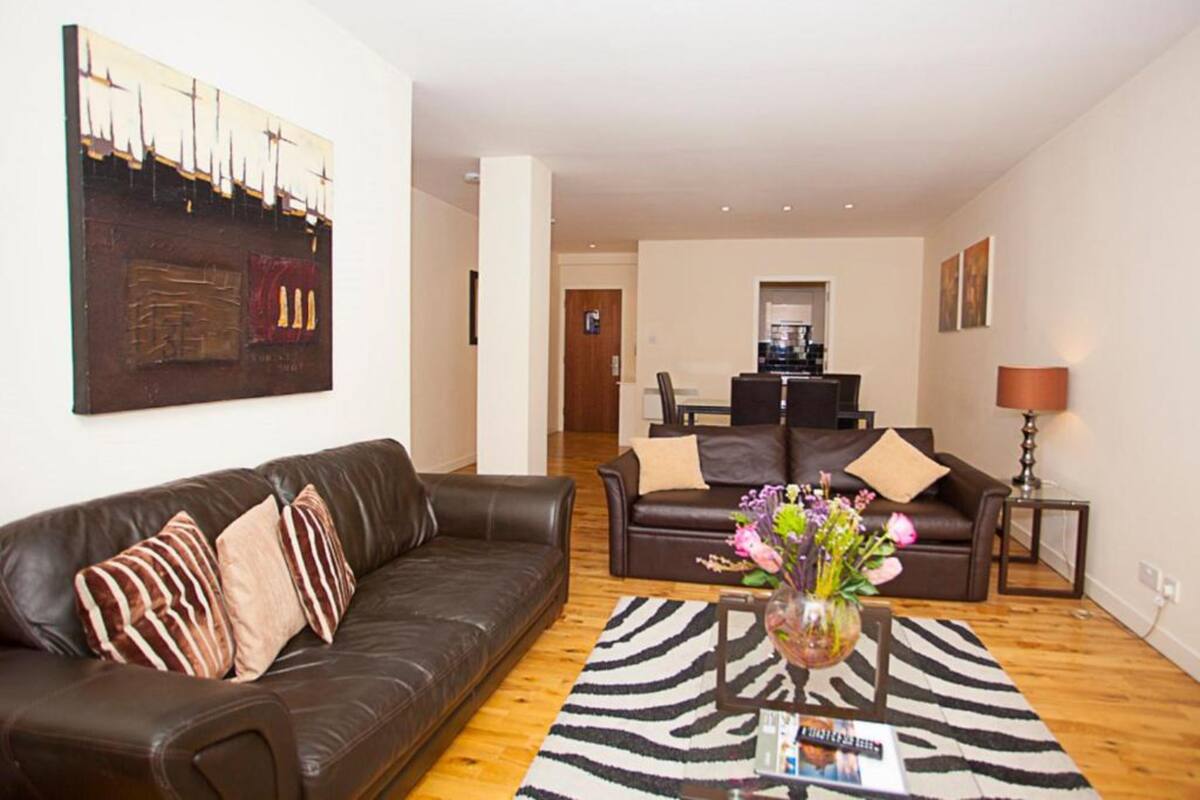 A modern living room with two sofas, a coffee table, and a zebra-patterned rug.