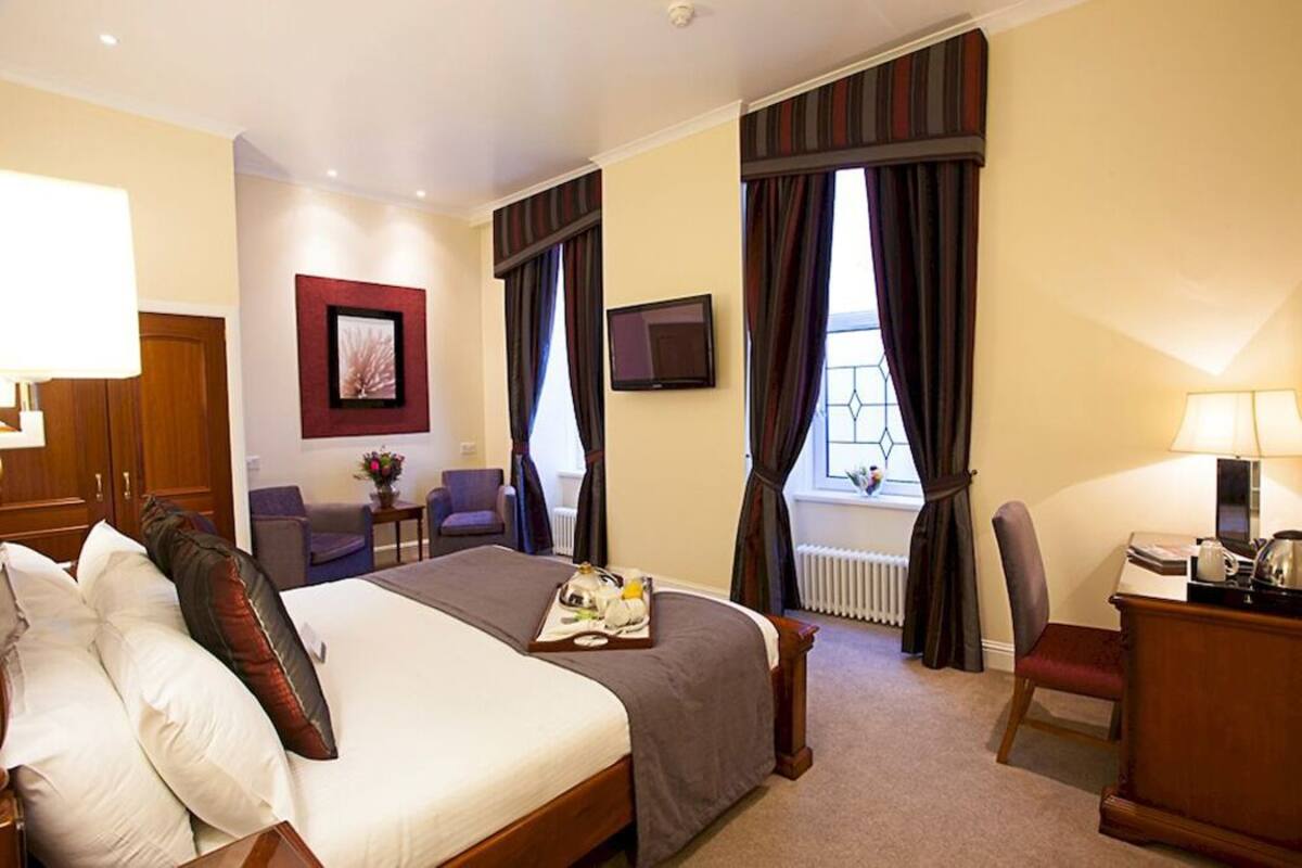 A hotel room with a bed, a desk, a chair, a television, and a window with curtains.