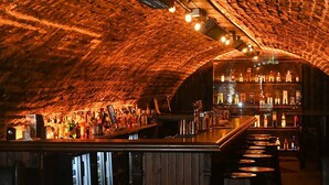 An underground bar with a rustic brick ceiling, wooden bar counter, and stools. - Aberdeen Douglas Hotel (Aberdeen)