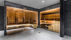 Een moderne sauna met houten lambrisering en glazen deuren, een bank en een bankje met een handdoek.