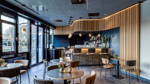 Een modern restaurantinterieur met ronde tafels, barstoelen en een toonbank met een houten paneeldecor.