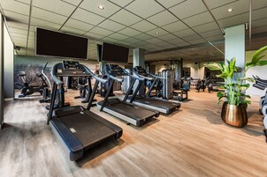 Un gimnasio con cintas de correr, bicicletas estáticas y máquinas de pesas.