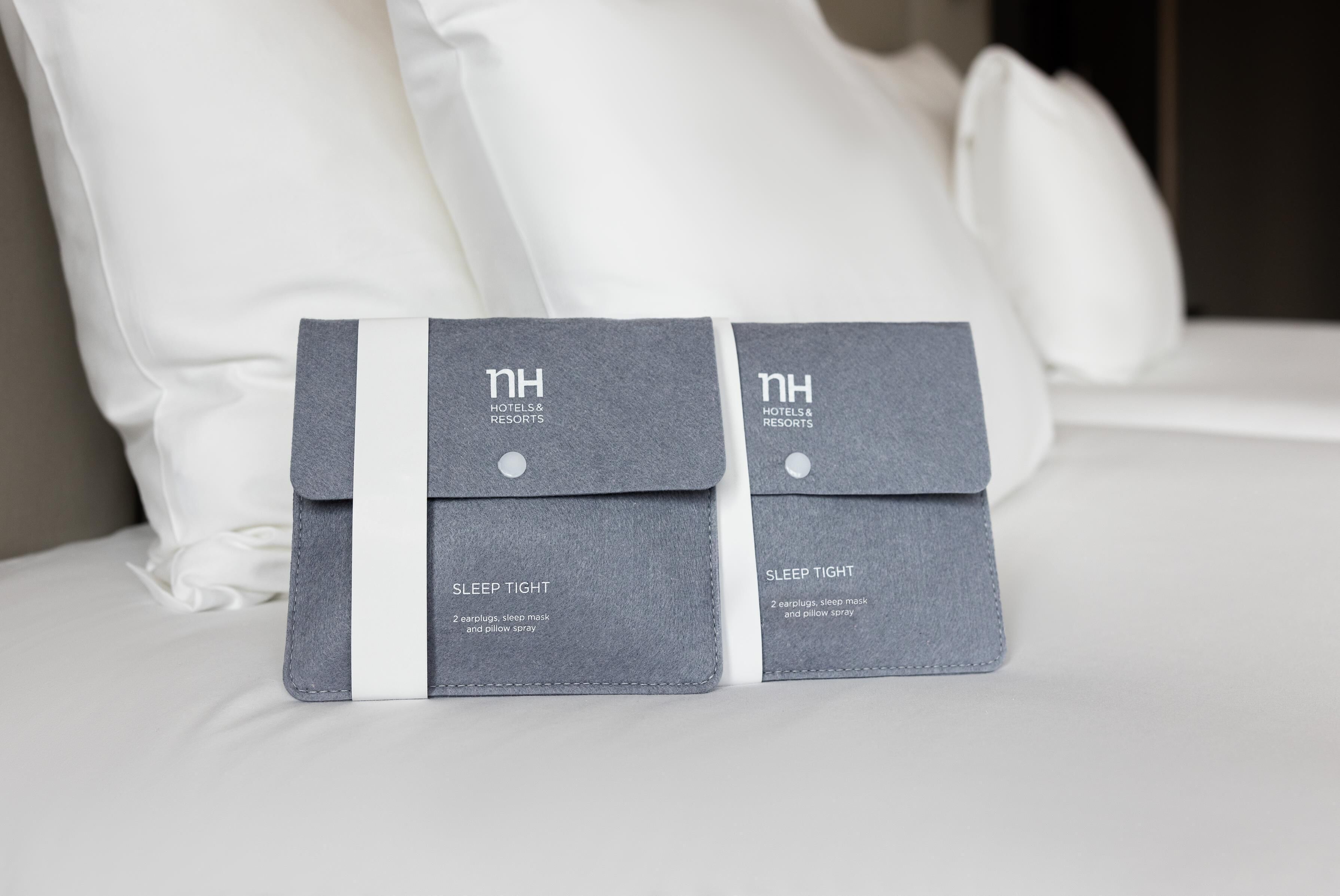 Two grey sleep tight packages on a bed with white pillows.