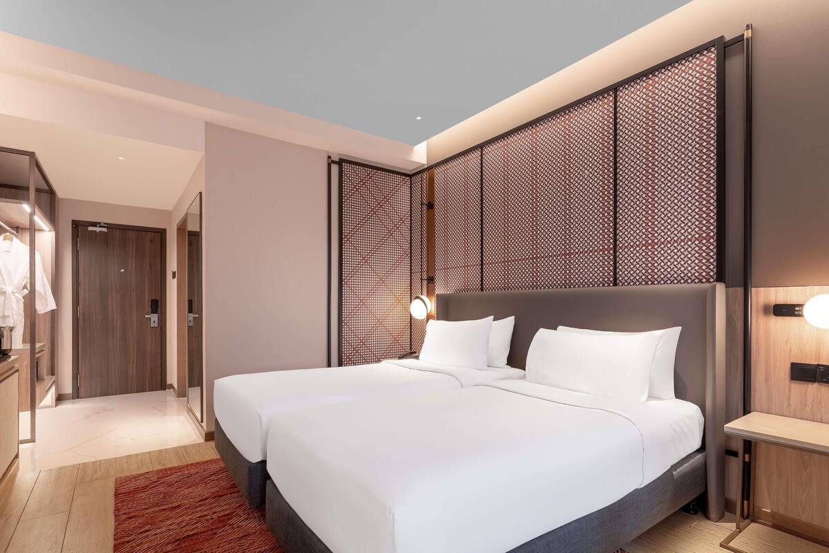 Ein modernes Hotelzimmer mit einem großen Bett, einem Nachttisch, einem Kleiderschrank und einer dekorativen Wandverkleidung.