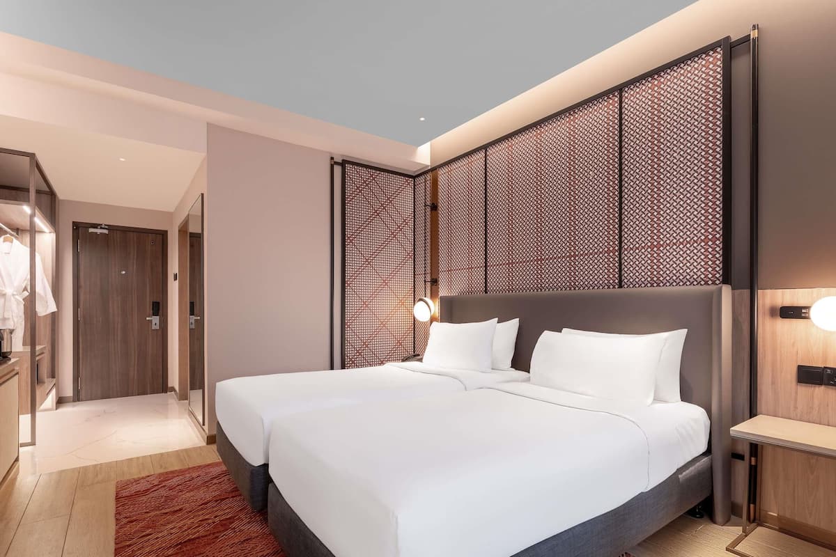Une chambre d’hôtel moderne dotée d’un grand lit, d’une table de chevet, d’une armoire et d’un panneau décoratif mural.