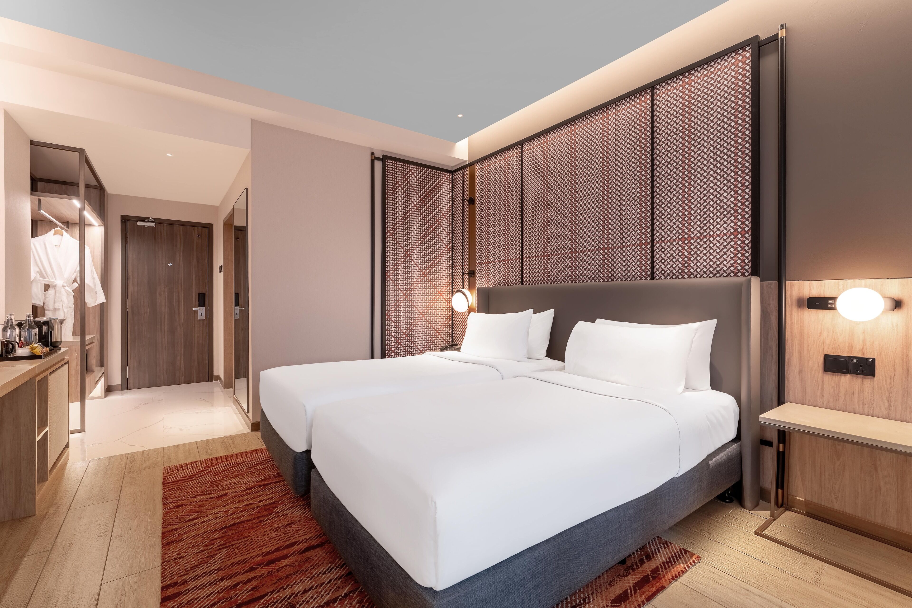 A modern hotel room with two beds, a walk-in closet, and a large window.