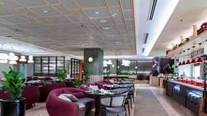 A modern restaurant interior with seating, a kitchen area, and a patterned floor. - Grand Mercure Kuala Lumpur Bukit Bintang (Kuala Lumpur)