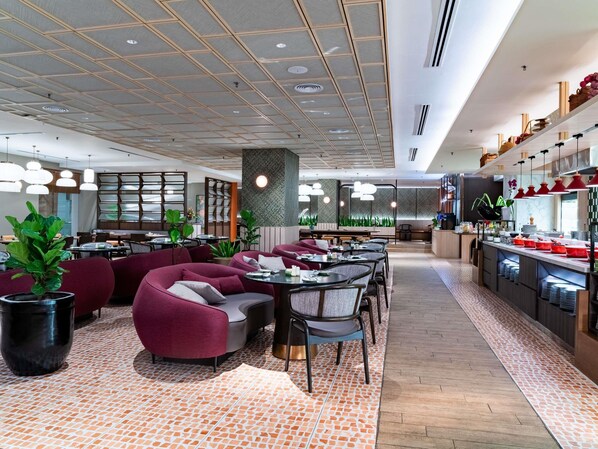 Ein modernes Restaurant mit Sitzgelegenheiten, einer Küchenzeile und einem gemusterten Boden.