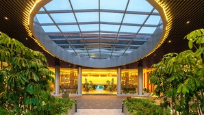 A modern hotel lobby with a large skylight, columns, and indoor plants. - Swiss-Grand Beach Resort Kuantan (Kuantan)