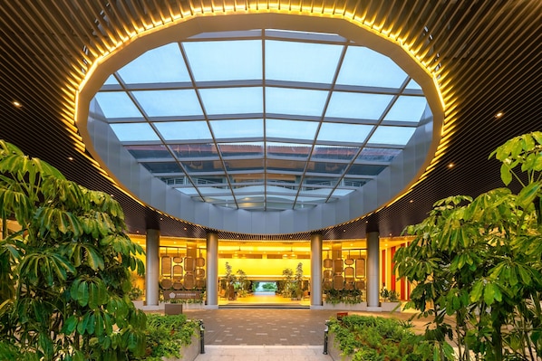 A modern hotel lobby with a large skylight, columns, and indoor plants. - Swiss-Grand Beach Resort Kuantan (Kuantan)