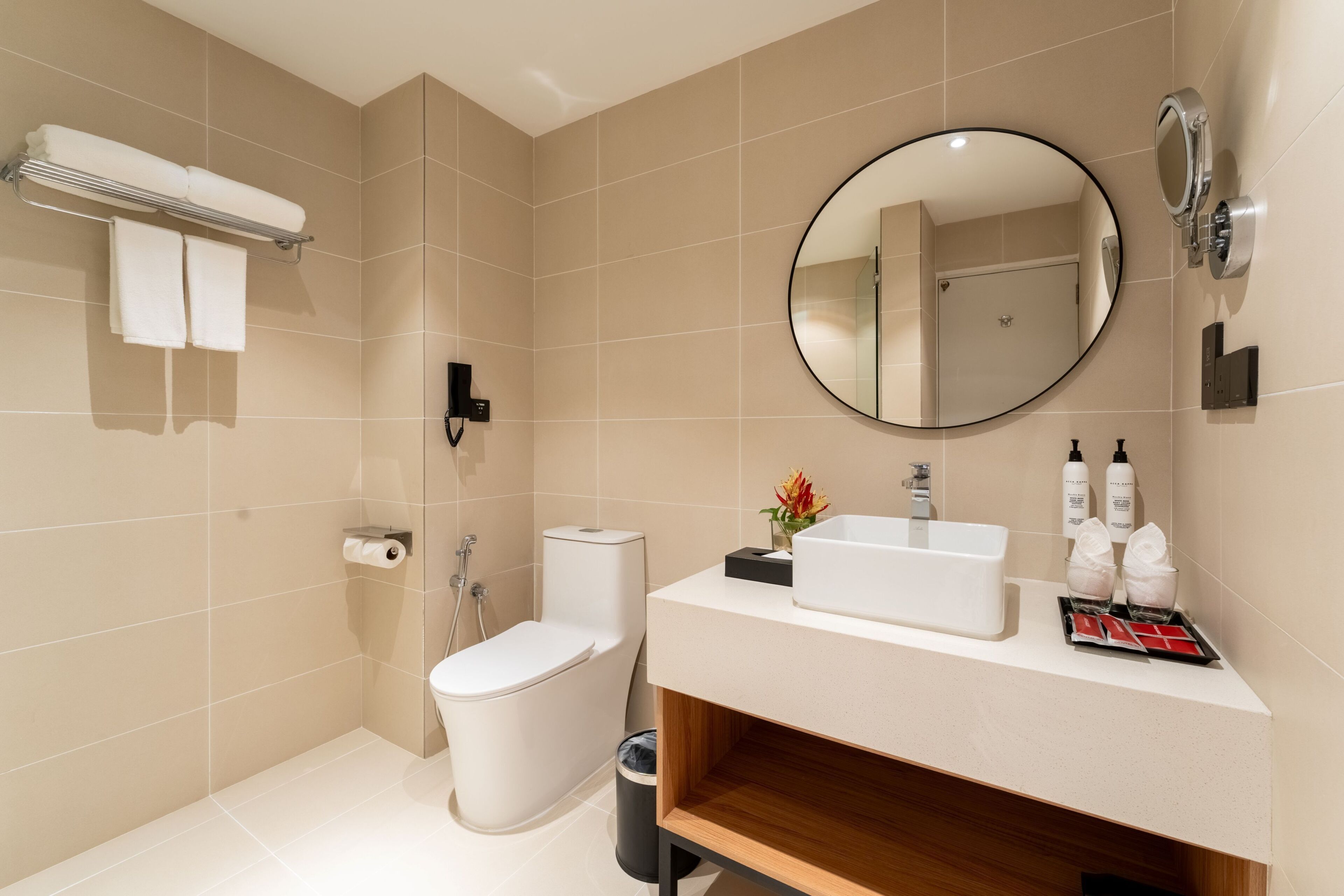 A modern bathroom with a toilet, bidet, sink, and mirror.