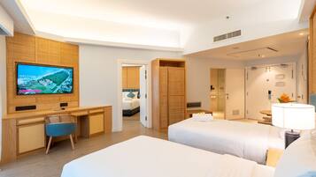 A hotel room with a TV, two beds, a desk, and a chair.