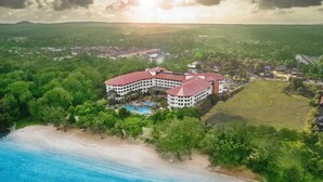 A large resort with a pool, surrounded by lush greenery and a beach. - Swiss-Grand Beach Resort Kuantan (Kuantan)