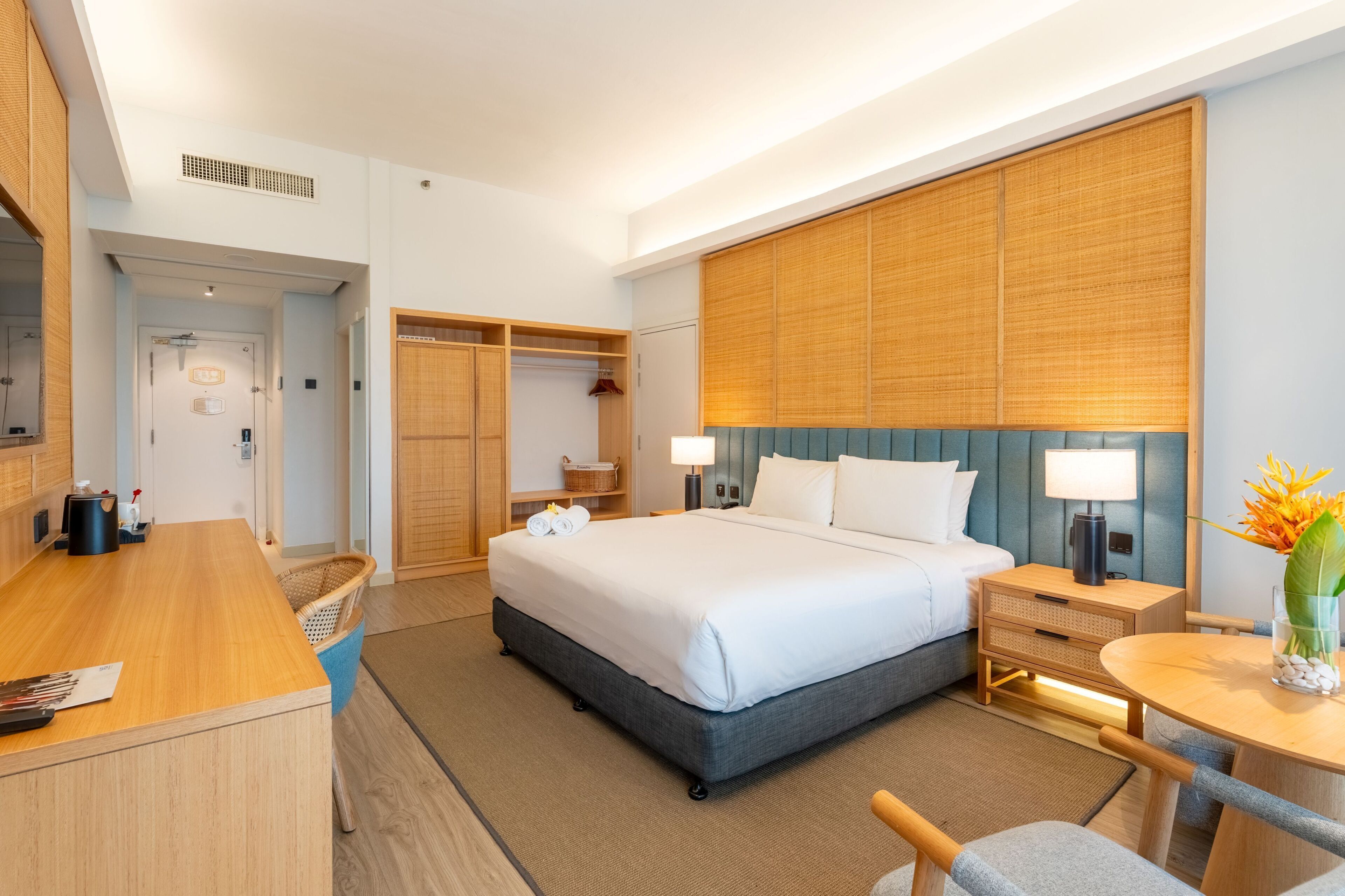 Ein Hotelzimmer mit Bett, Nachttischen, einem Schreibtisch, einem Sessel, einem kleinen Tisch mit einer Vase und einem Kleiderschrank.
