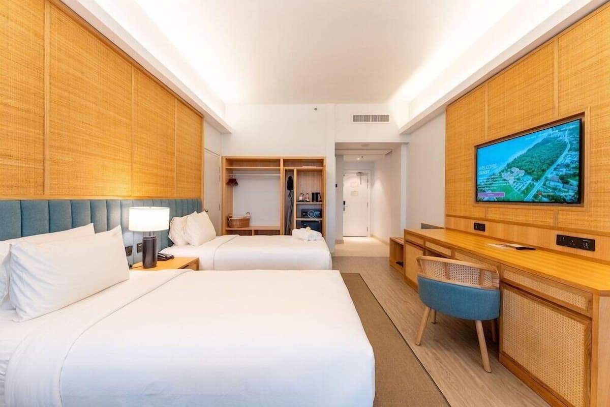 Ein Hotelzimmer mit zwei Betten, einem Schreibtisch, einem Fernseher und einem Kleiderschrank.