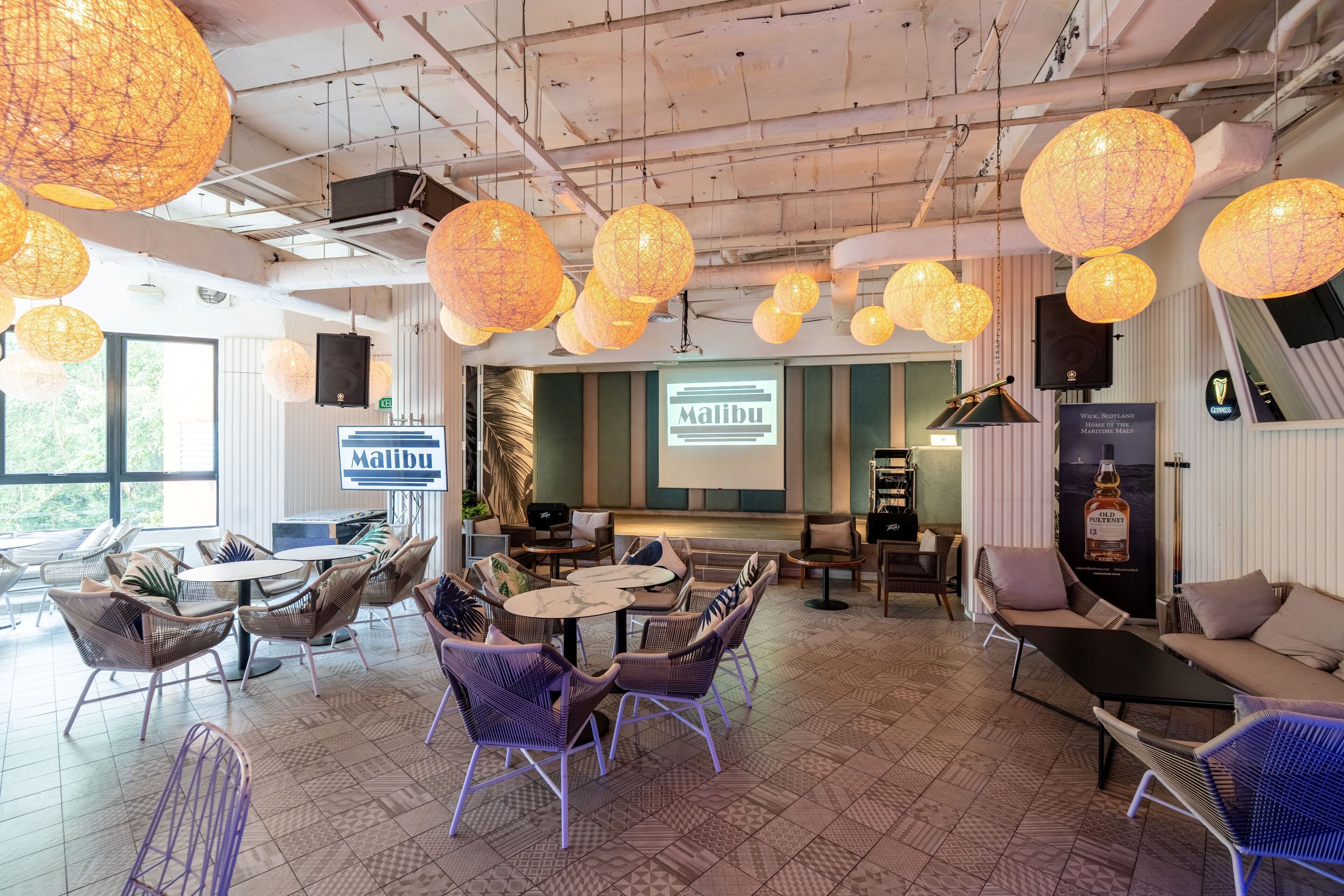 A modern lounge area with wicker furniture, patterned flooring, and hanging paper lanterns.