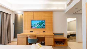 A hotel room with a bed, a desk, a television, and a shoe storage area.