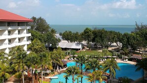 A resort with a large pool, palm trees, and a view of the ocean. - Swiss-Grand Beach Resort Kuantan (Kuantan)