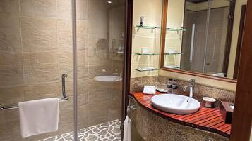 A modern bathroom with a glass shower enclosure, a granite countertop, a white sink, and a large mirror.