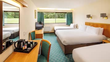 A hotel room with two beds, a TV, a coffee station, and a view of the outdoors.