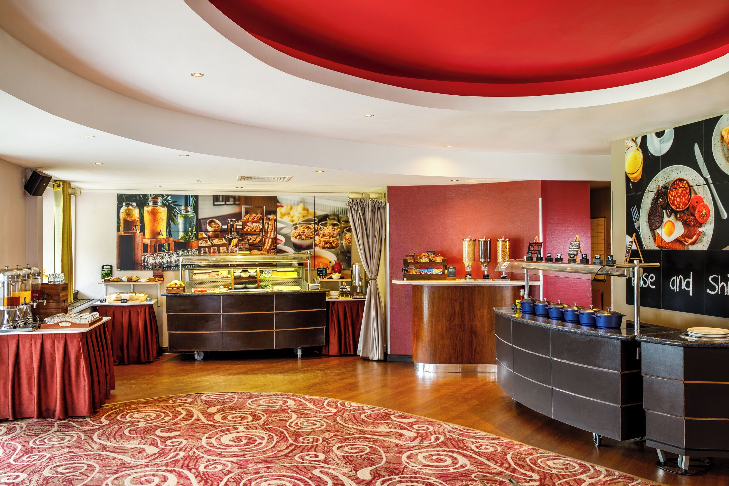 A breakfast buffet with various food items and beverages, a coffee station, and a counter with a menu.