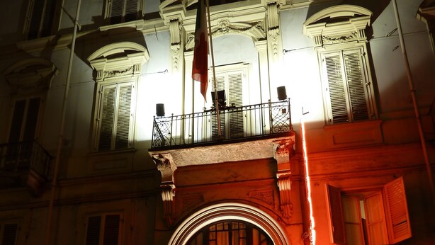 Ein Gebäude mit einem markanten Eingang, einem Balkon und einer Flagge.