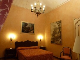 Una camera da letto con un letto, due lampade a parete, un lampadario e due quadri.