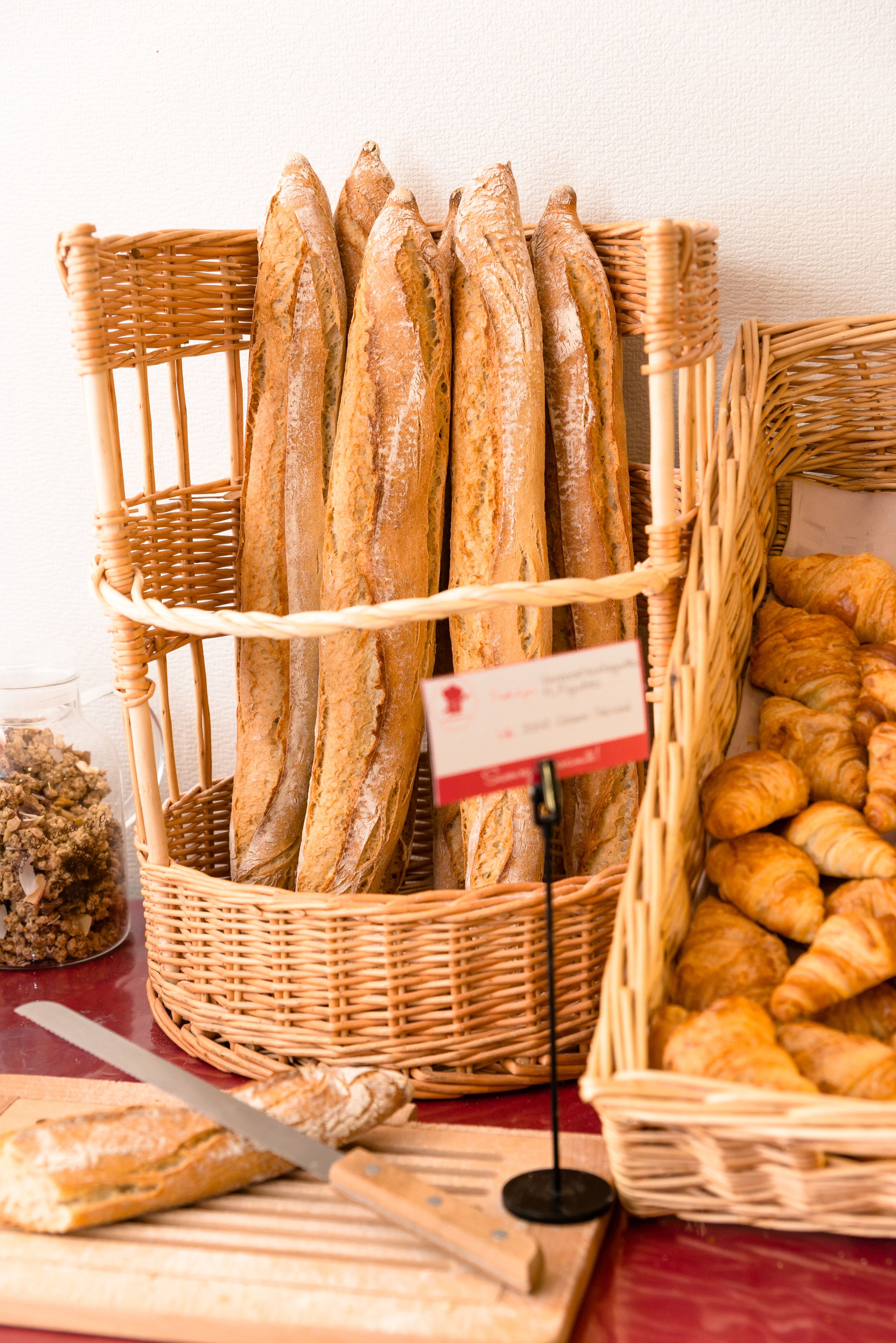 A basket of baguettes and croissants on a table.