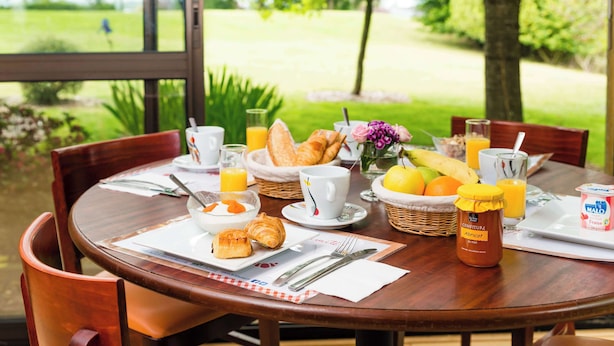 Una mesa de desayuno con croissants, zumo de naranja y un tarro de miel.