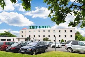 Um estacionamento em frente a um hotel com uma placa indicando "BRIT HOTEL".