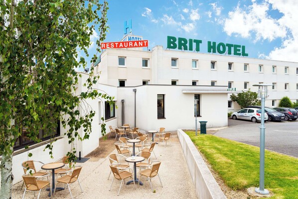 A hotel with outdoor seating and a restaurant sign.