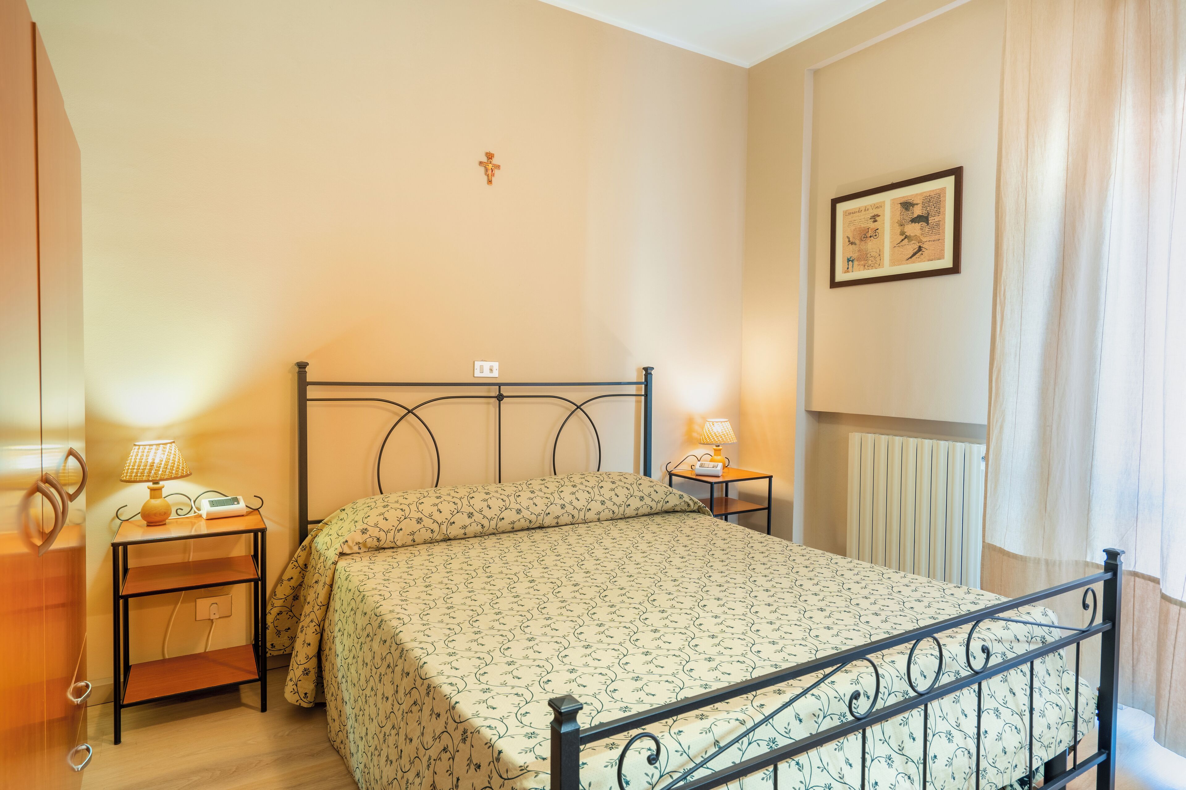 Une chambre à coucher comprenant un lit, des lampes de chevet, une table de chevet, un luminaire fixé au mur et un tableau encadré.
