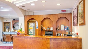 Ett välkomstområde med en receptionsdisk i trä, en svart läderstol och en röd matta.