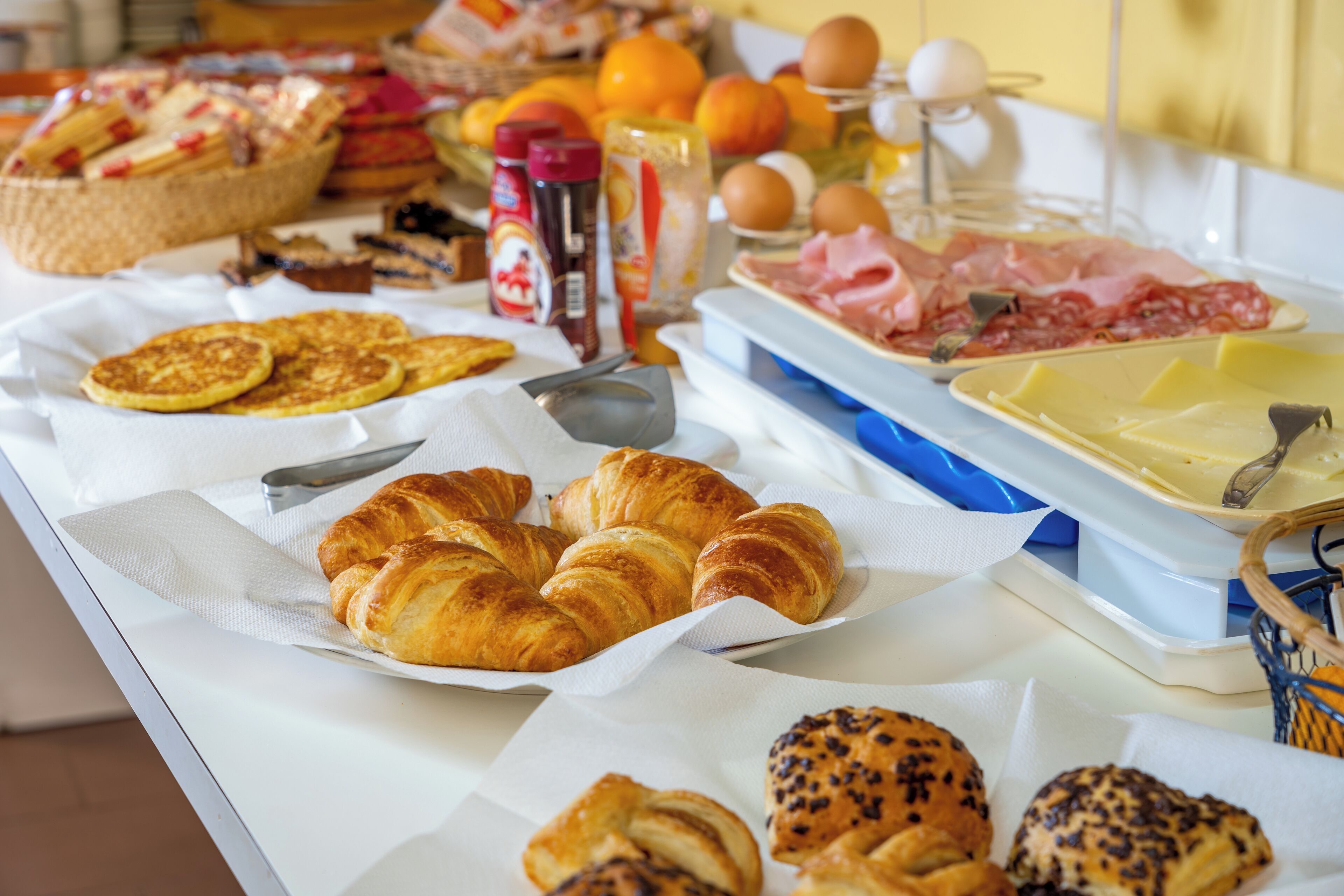 Un buffet de petit-déjeuner proposant une variété de viennoiseries, de charcuteries et de fruits.