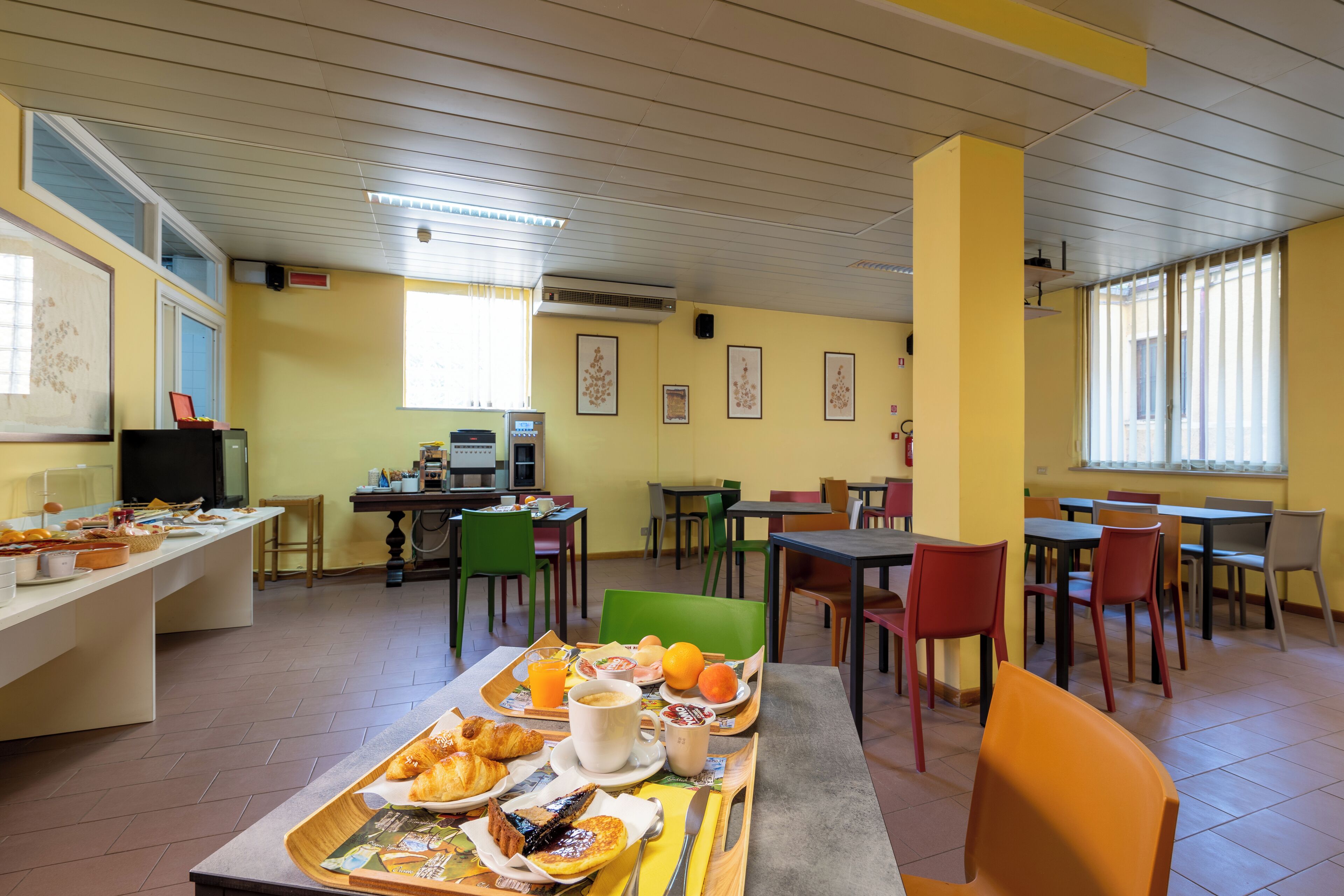 A dining area with tables and chairs, a buffet table with food and drinks, and a television on a stand.
