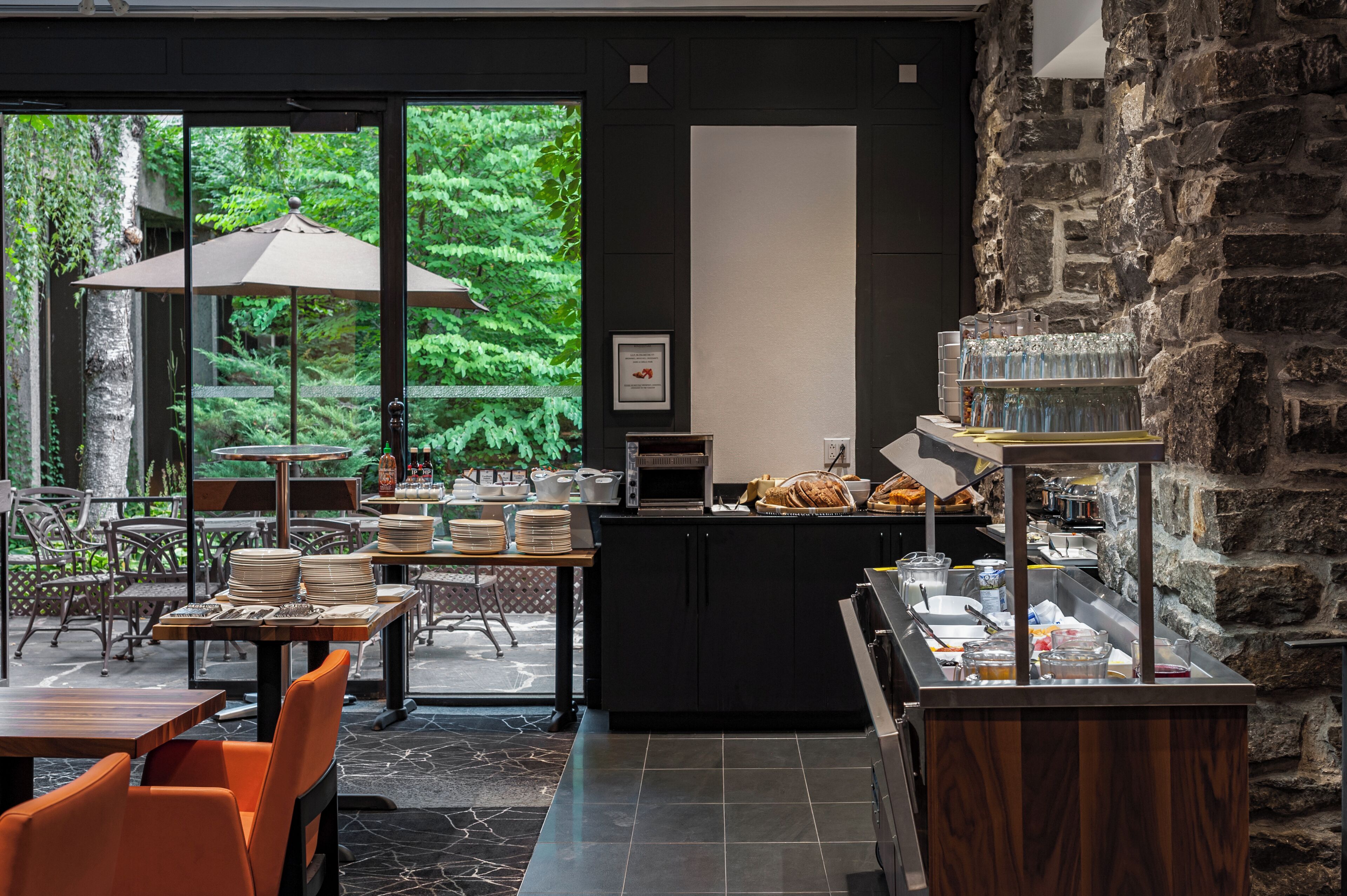 Un restaurante con terraza, un mostrador de buffet y una pared de piedra.