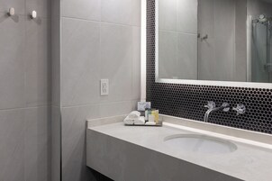 A modern bathroom with a large mirror, a sink, and a shower.